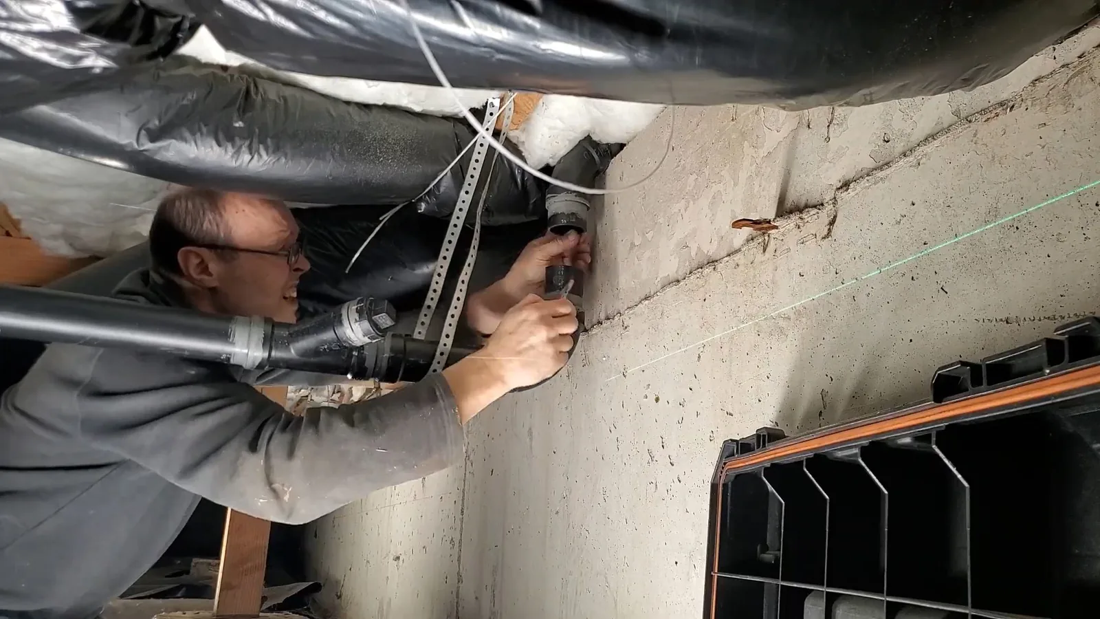 A technician crawling under a house to trace a leak, related to Crawl Space Plumbing questions homeowners ask