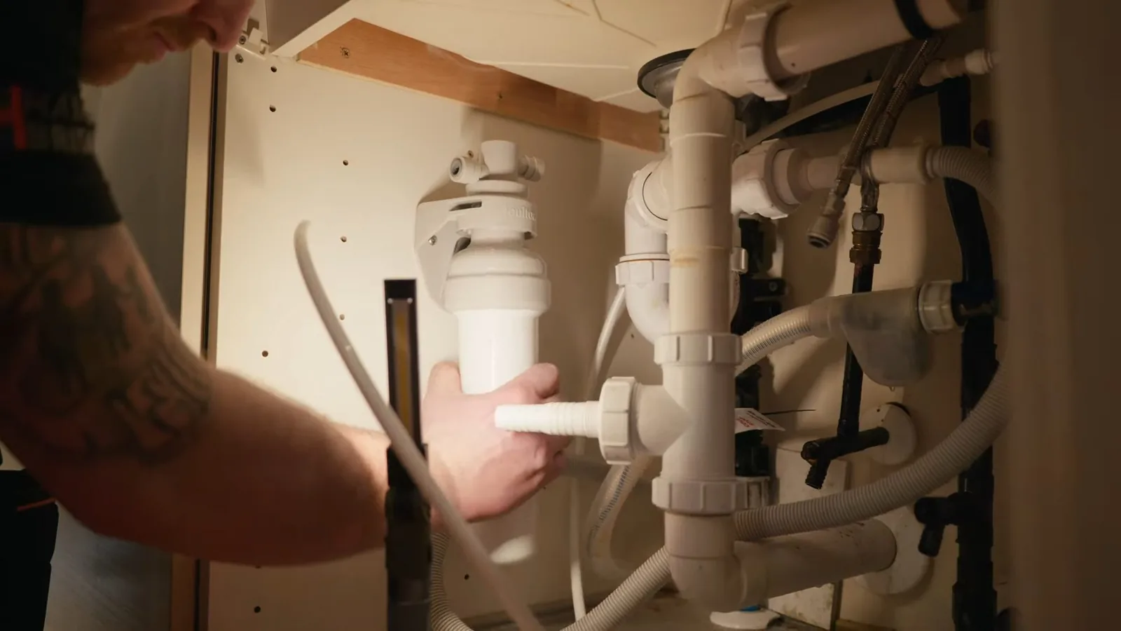 An RO system's storage tank connected below a kitchen sink during a service visit in Mansell