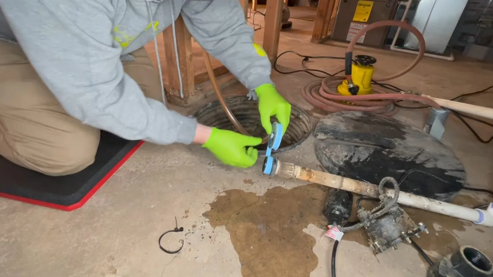 A sump pump discharge line routed out of a basement during a service visit in Old Milton