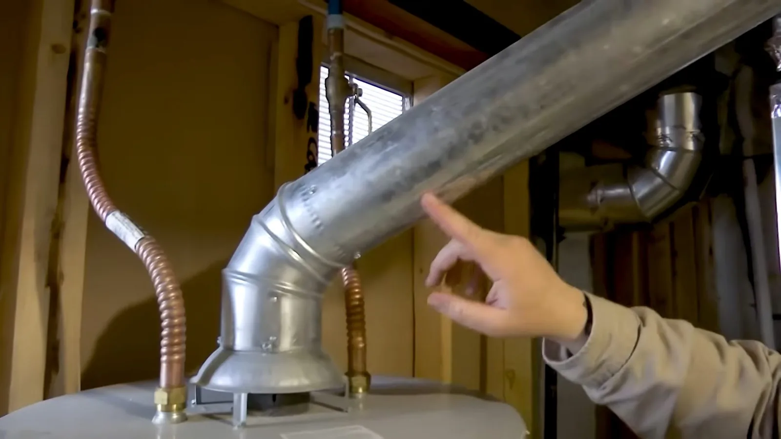 A technician inspecting a water heater's burner assembly, part of the team's day-to-day plumbing work